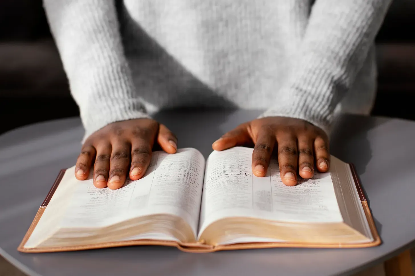 Des mains posées sur une Bible ouverte, en gros plan.