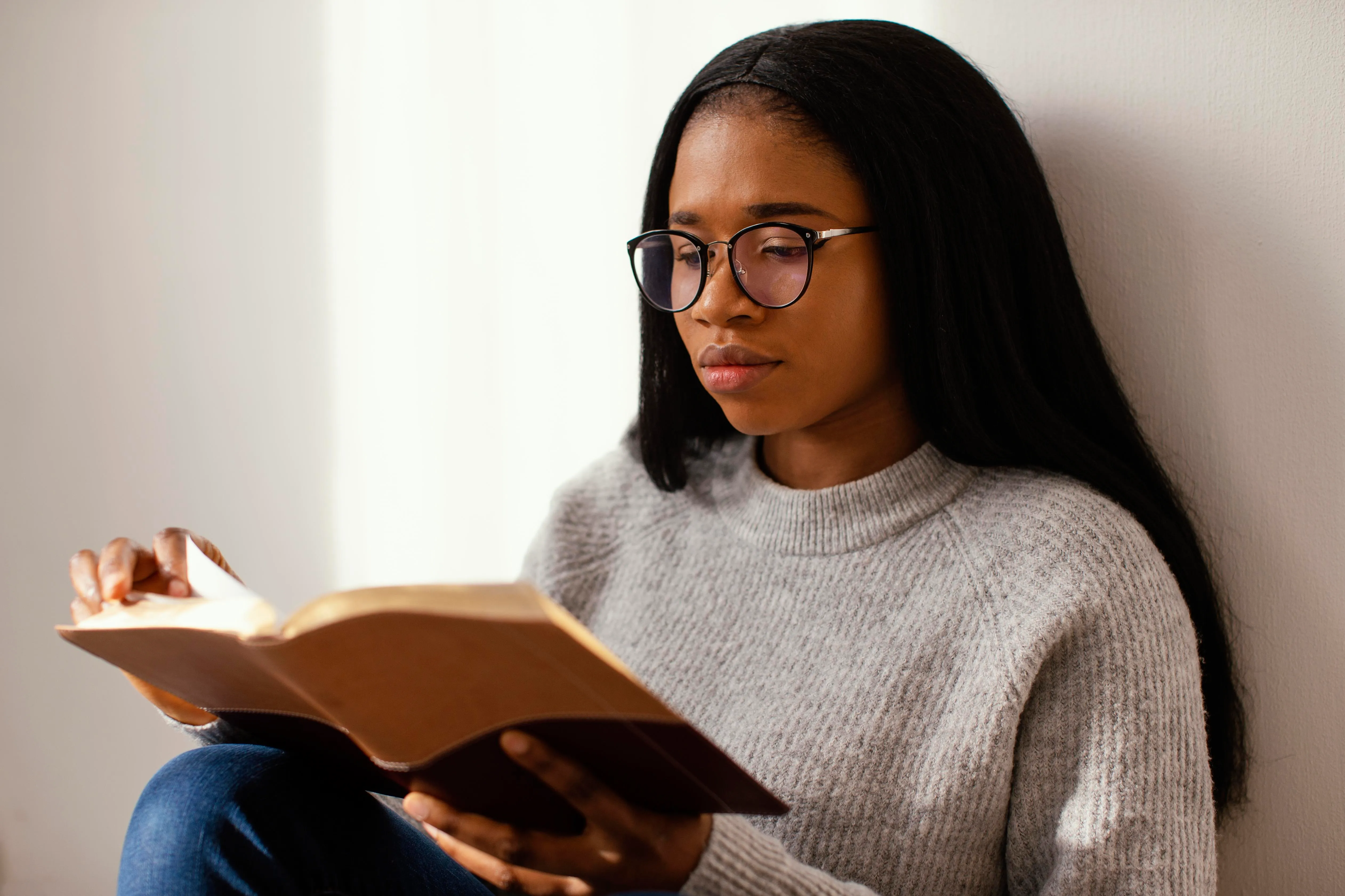 Une jeune femme à lunettes lisant attentivement une Bible.