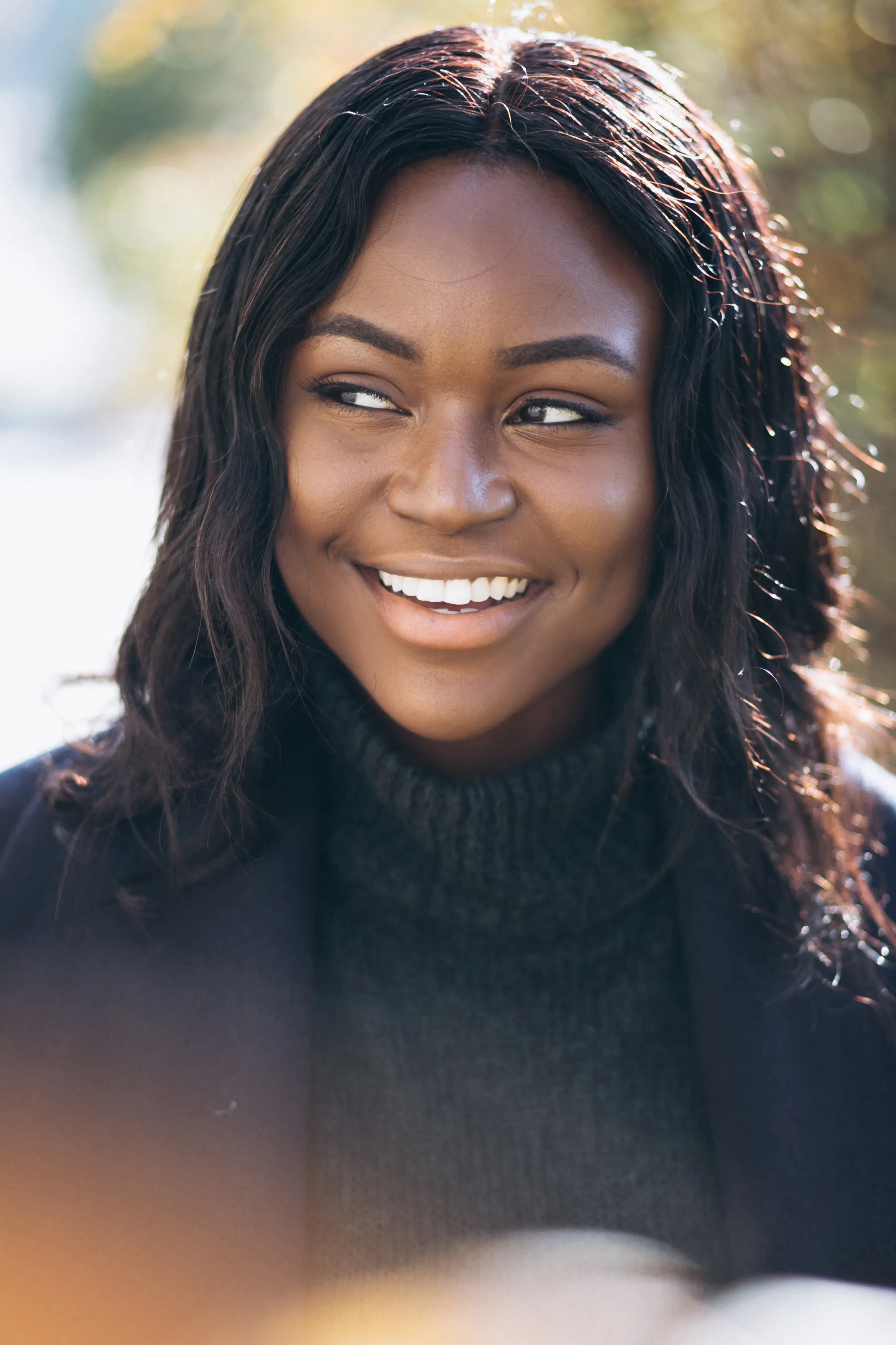 Une jeune femme souriante, le regard tourné sur le côté, dans un moment de légèreté.