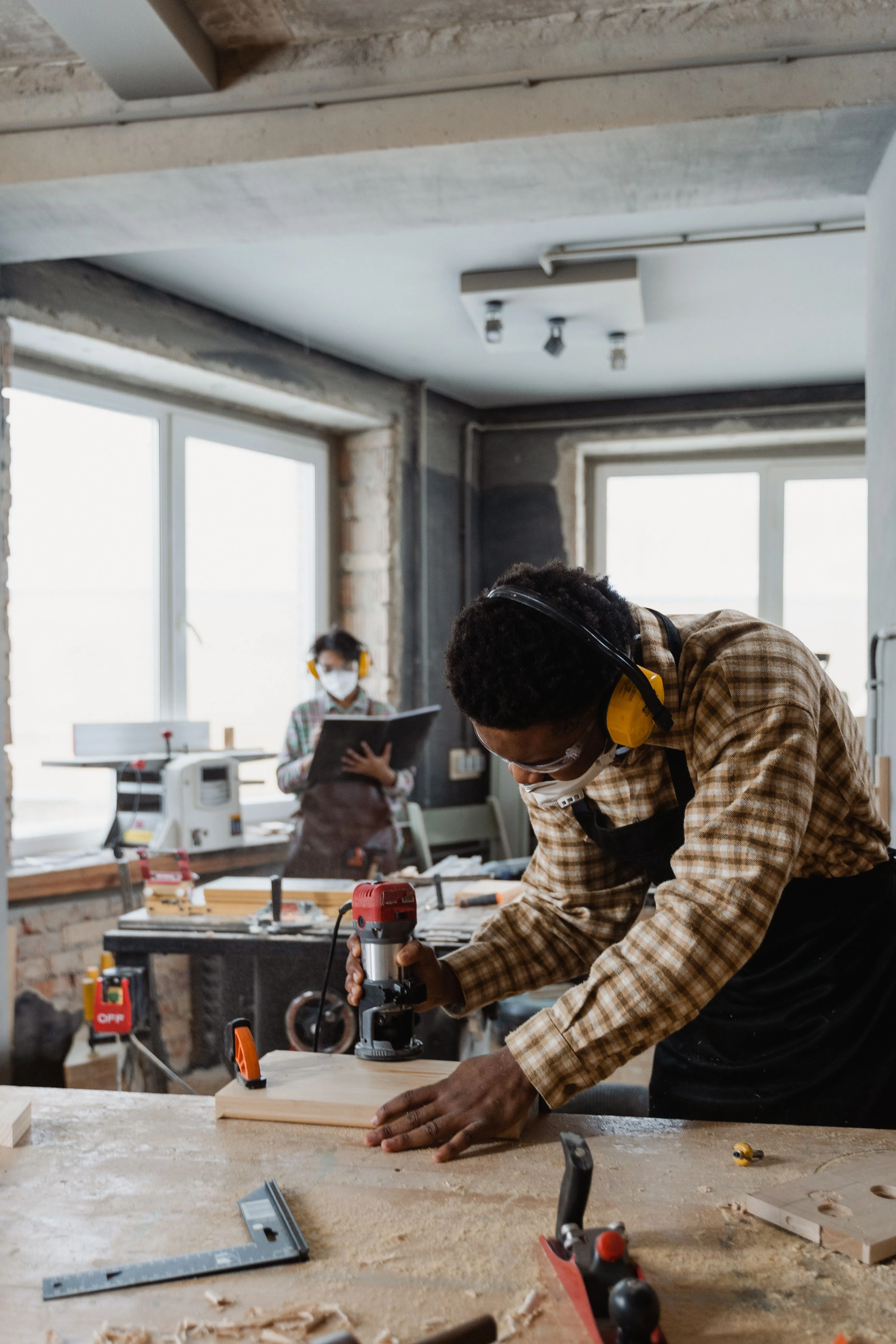 Un jeune homme au travail dans un atelier de menuiserie, concentré sur son ouvrage.