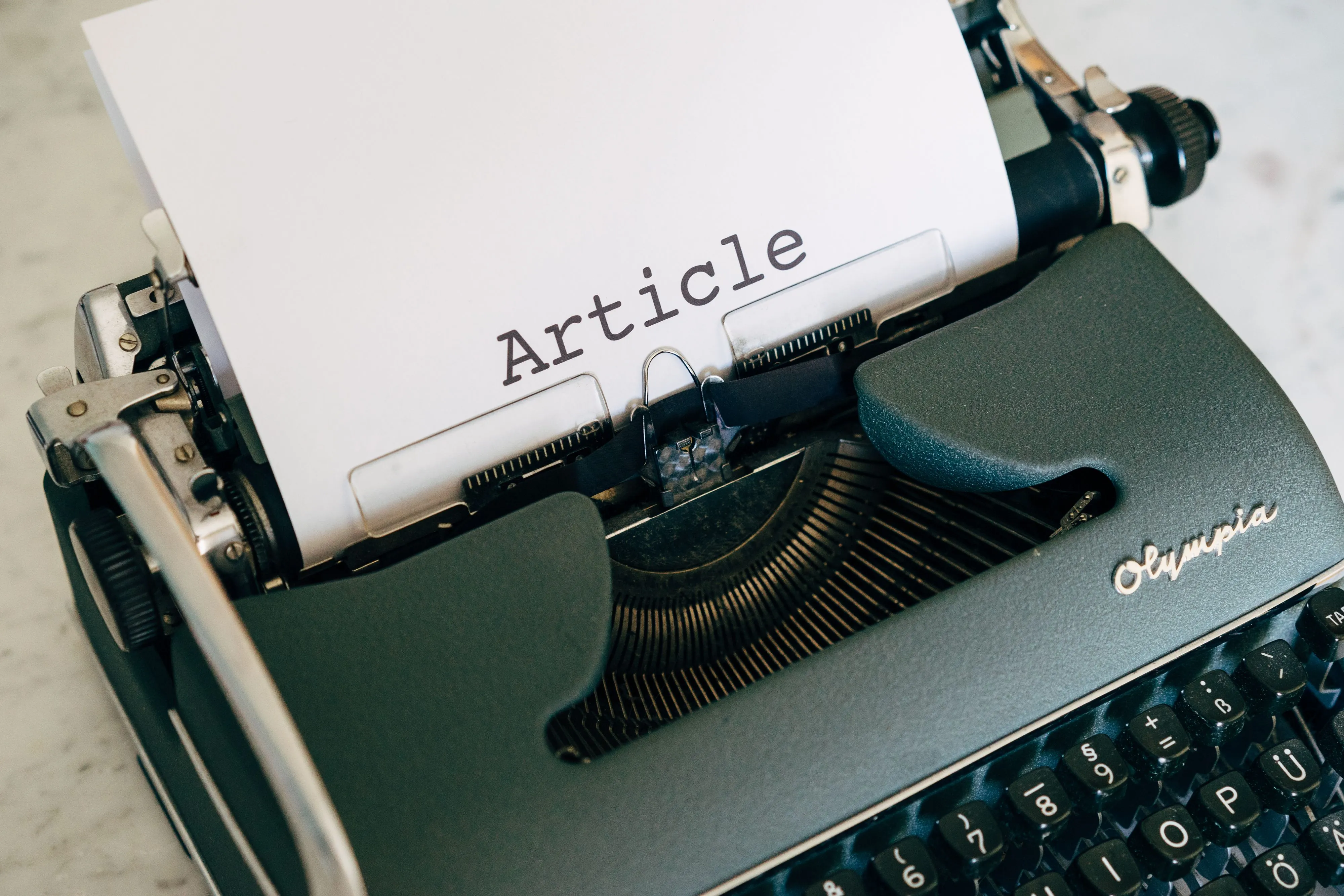 Une machine à écrire vintage Olympia avec une feuille portant le mot « Article ».