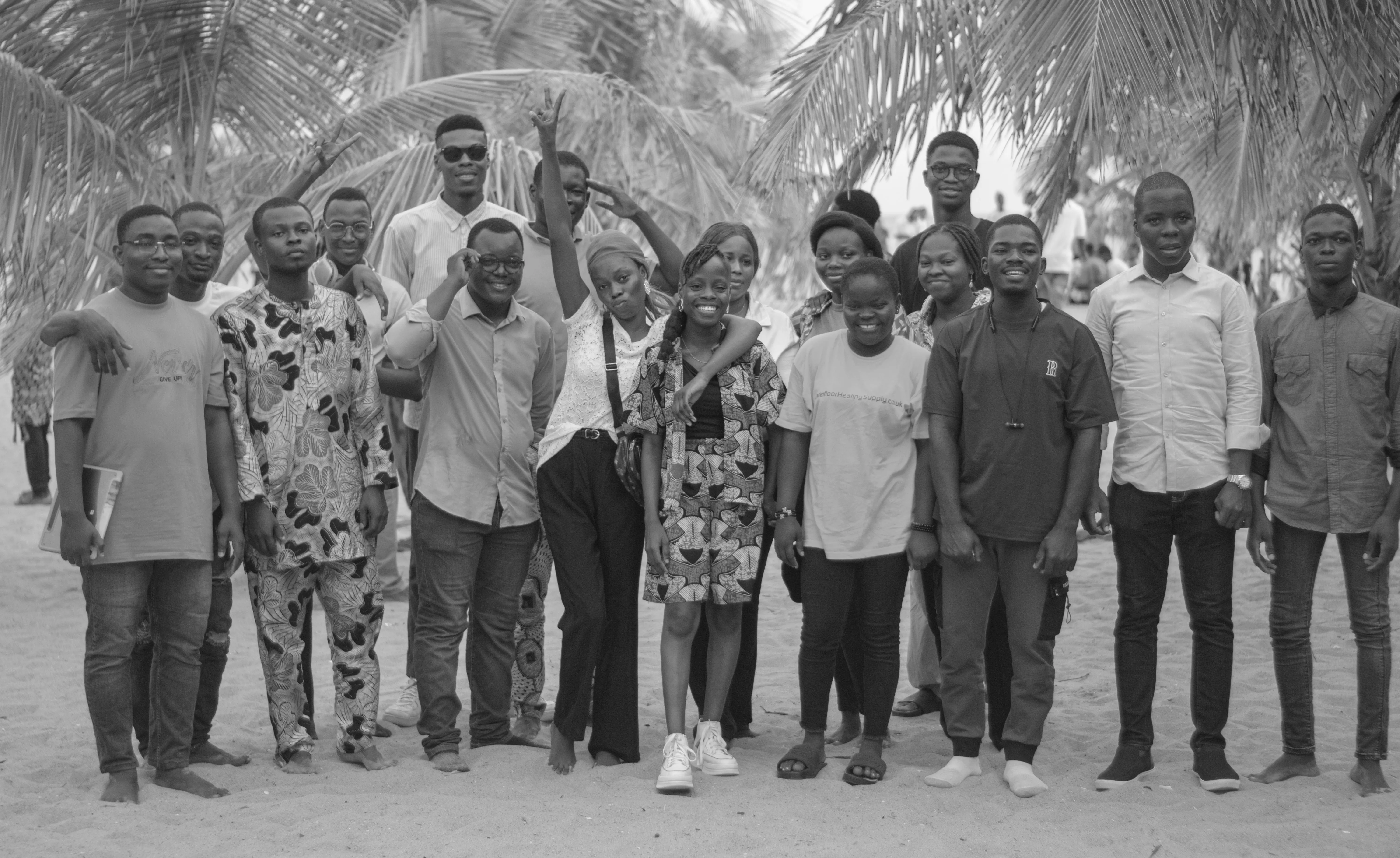 Groupe de jeunes adultes réunis sous des palmiers, souriants et complices.