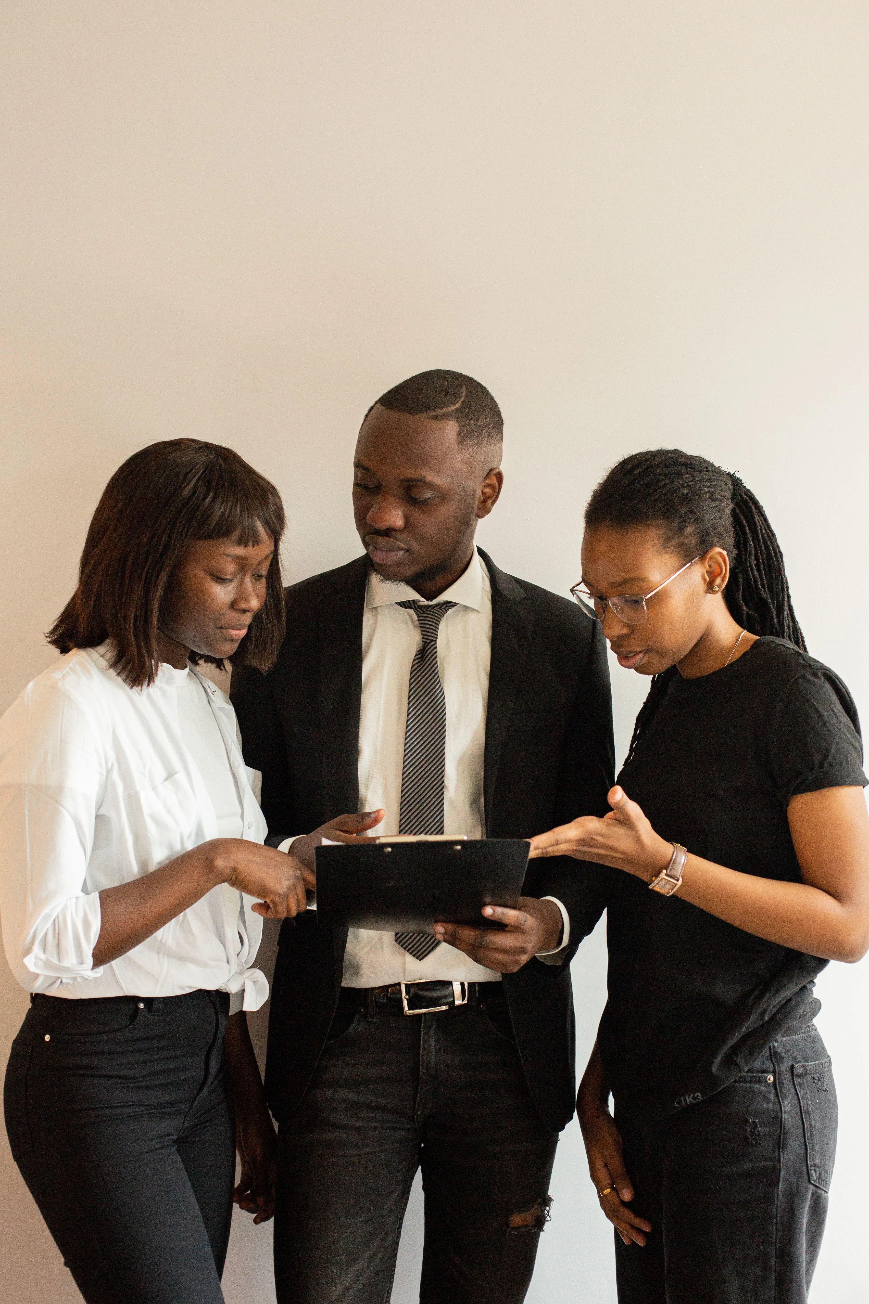 Trois jeunes professionnels penchés ensemble sur un document, en pleine discussion.