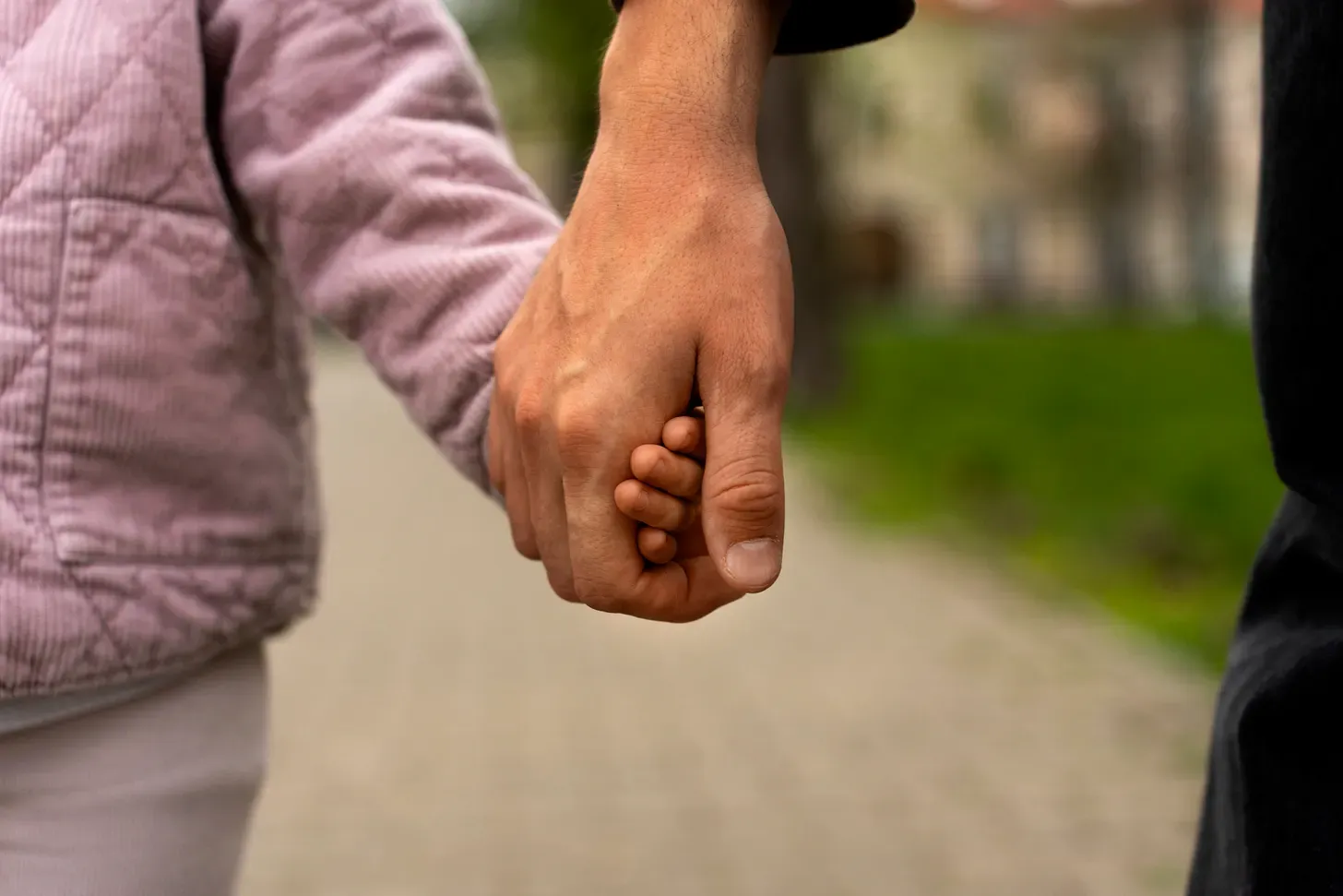Un adulte tenant la main d'un enfant, en gros plan.